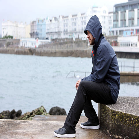 A young troubled man is sitting on stairs by the water
